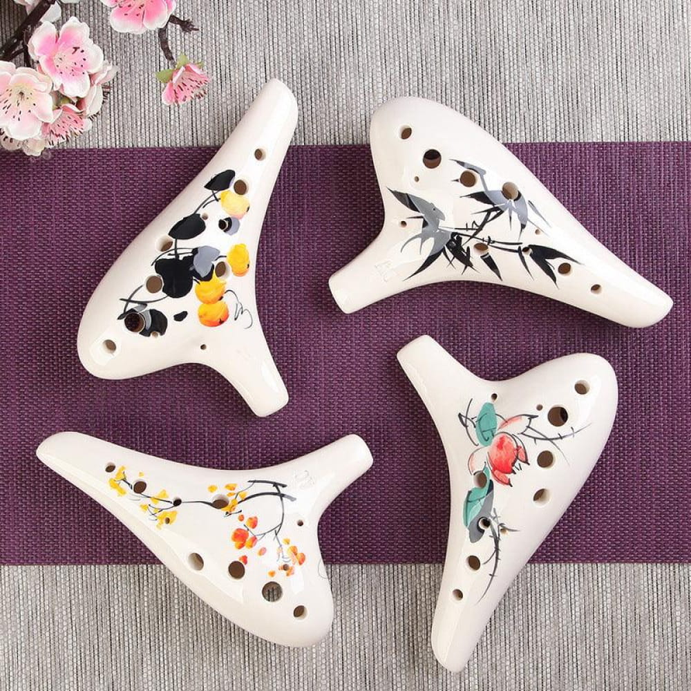 Four white ceramic ocarinas with floral and bird designs for beginners’ music
