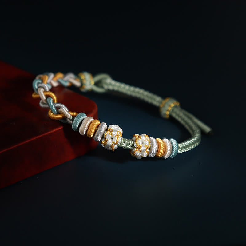 Bracelet à quatre brins avec fil rouge et fleur de pêcher