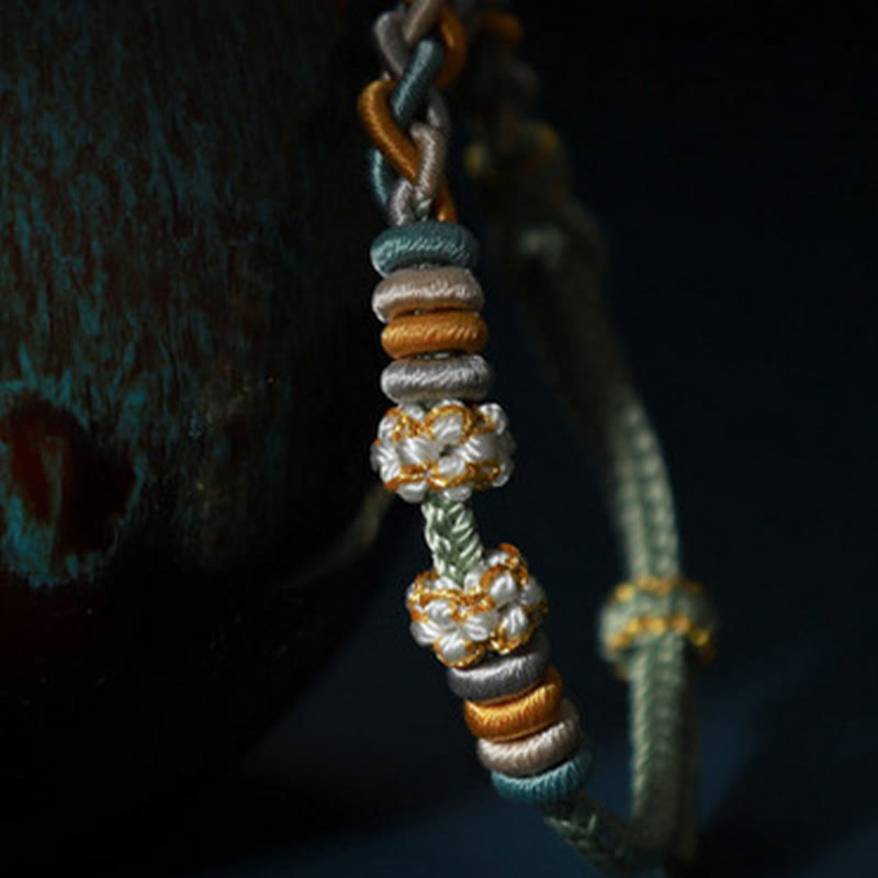 Bracelet à quatre brins avec fil rouge et fleur de pêcher