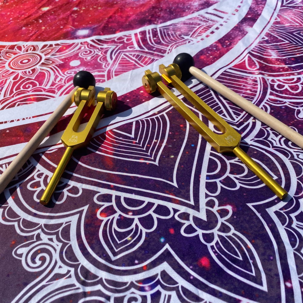 Two golden tuning forks with dampers and wooden mallets for healing sound therapy