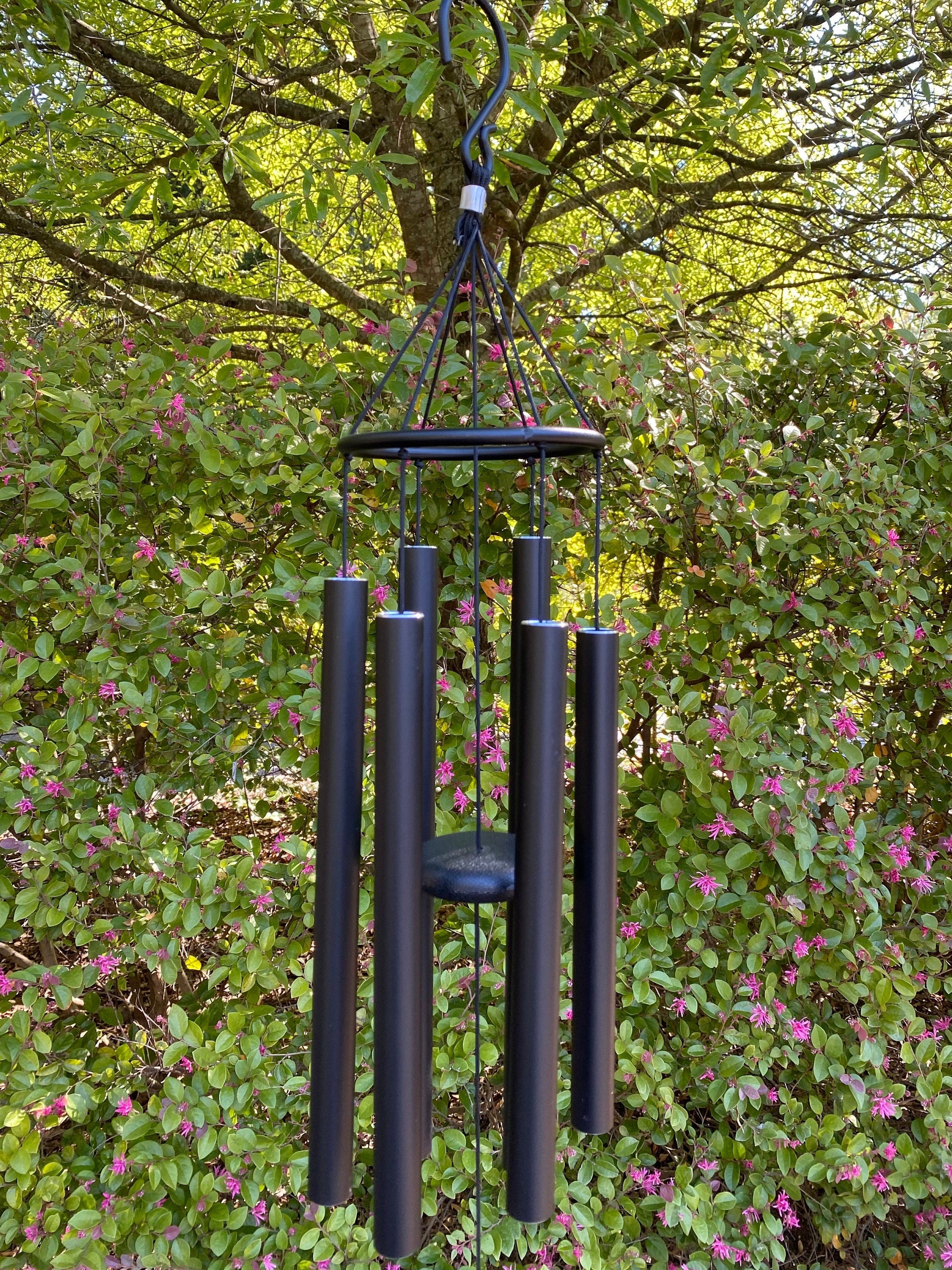 Black metal wind chimes with cylindrical tubes and circular top for outdoor use