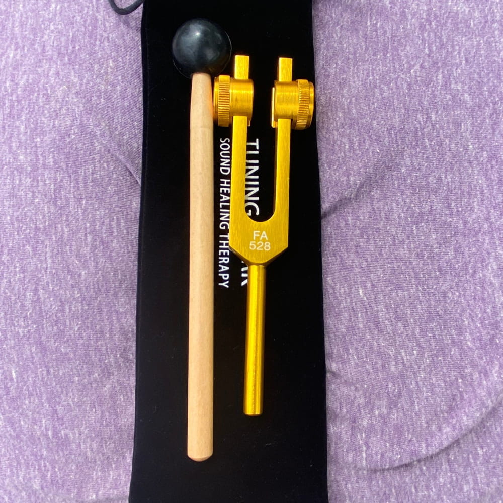 Yellow and beige 432 Hz and 528 Hz tuning forks with black striker for healing therapy