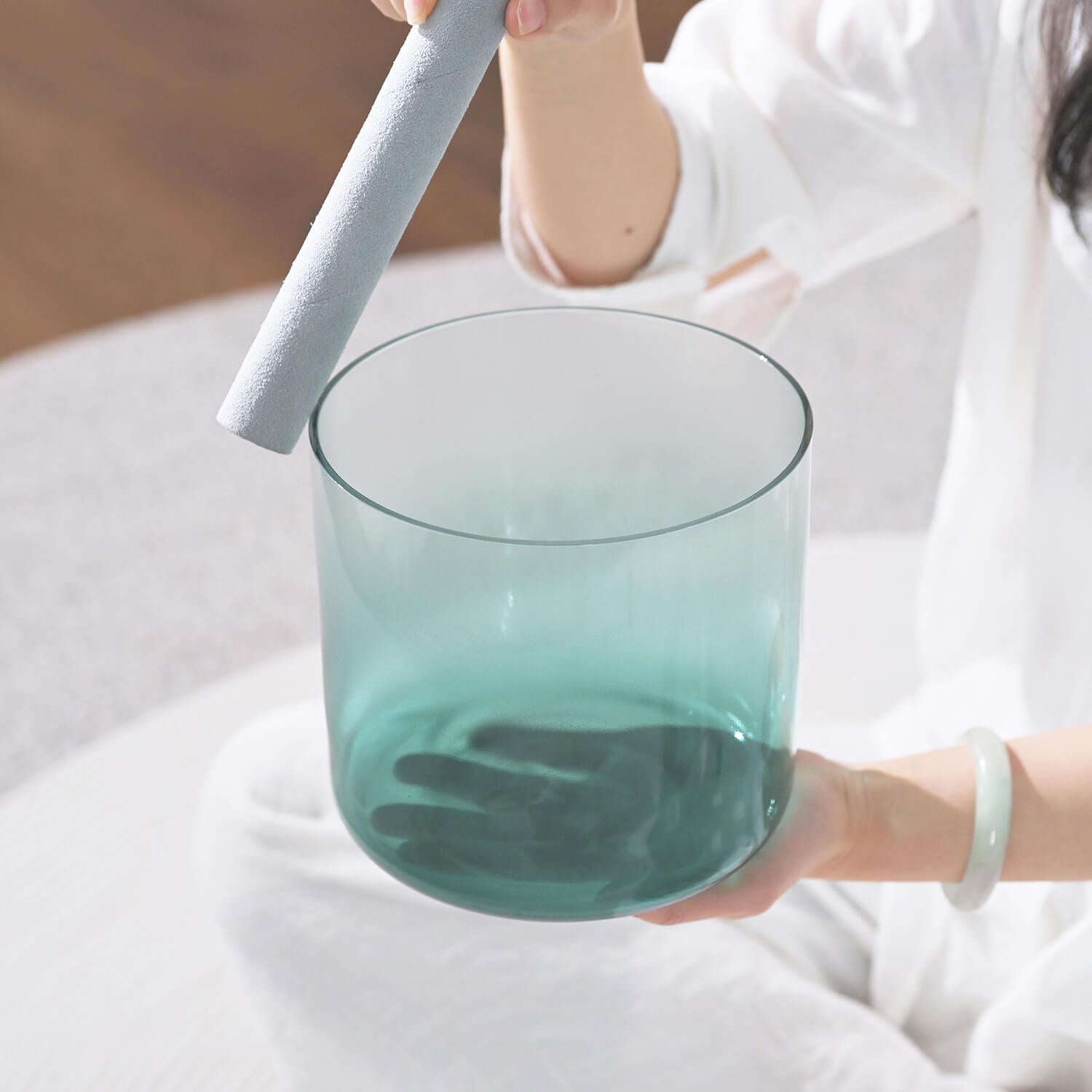 Turquoise-tinted glass tumbler held next to Quartz Crystal Singing Bowl for meditation healing