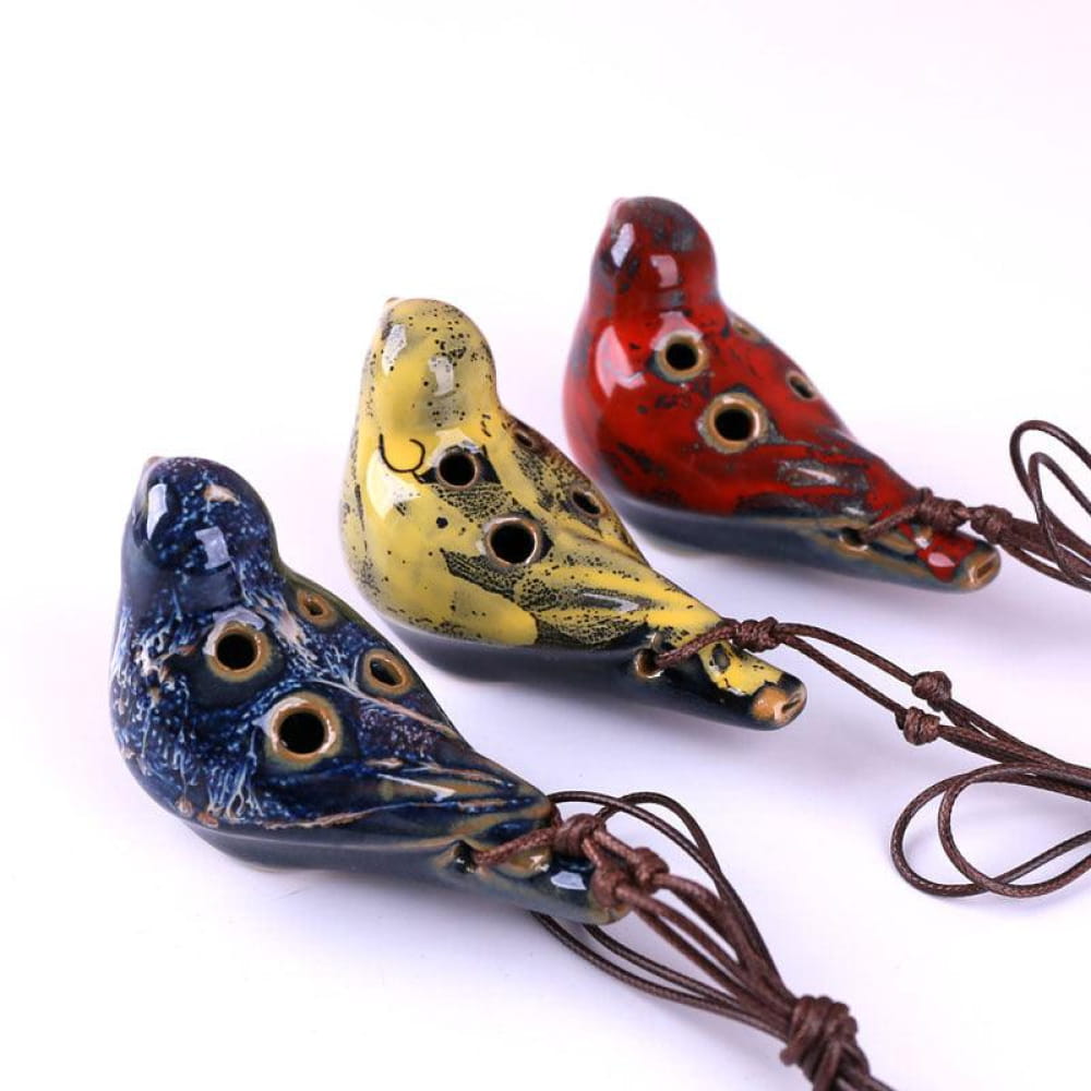 Three decorative ceramic bird pendants in blue, yellow, and red with leather cords