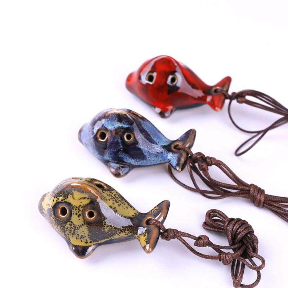 Decorative glass whale pendants with leather cords in red, blue, gold, and black