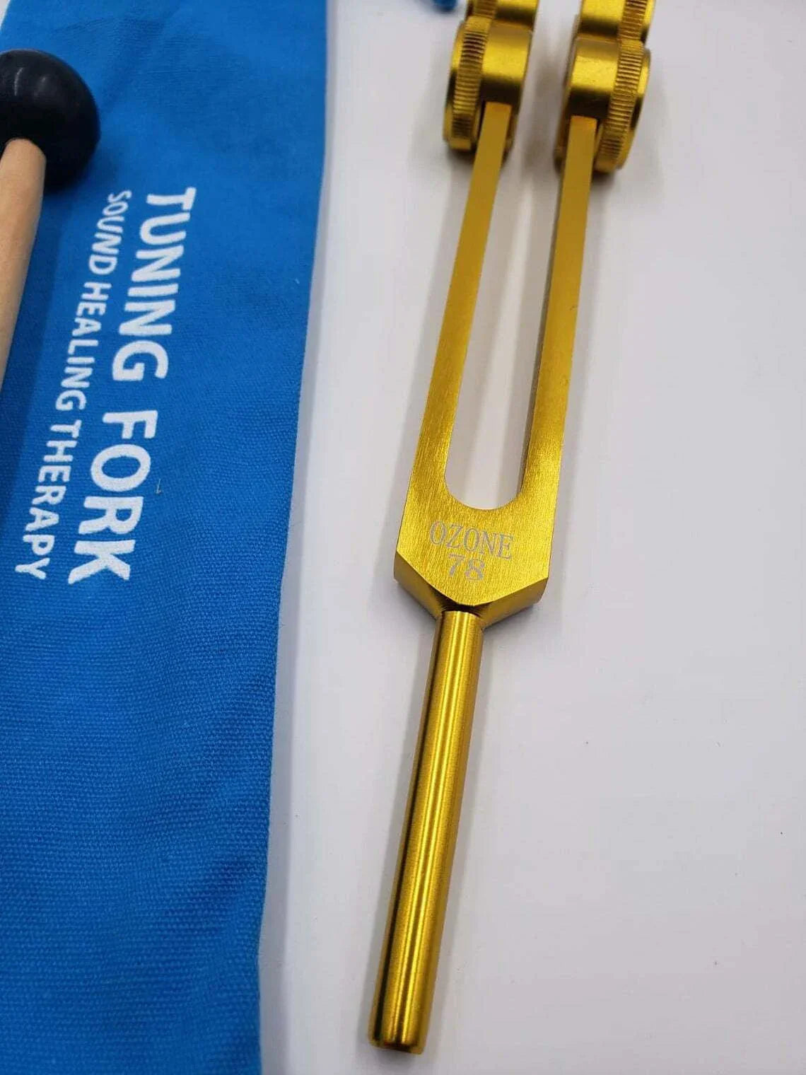 Gold-colored 78 Hz tuning fork with metal stem in healing activator set