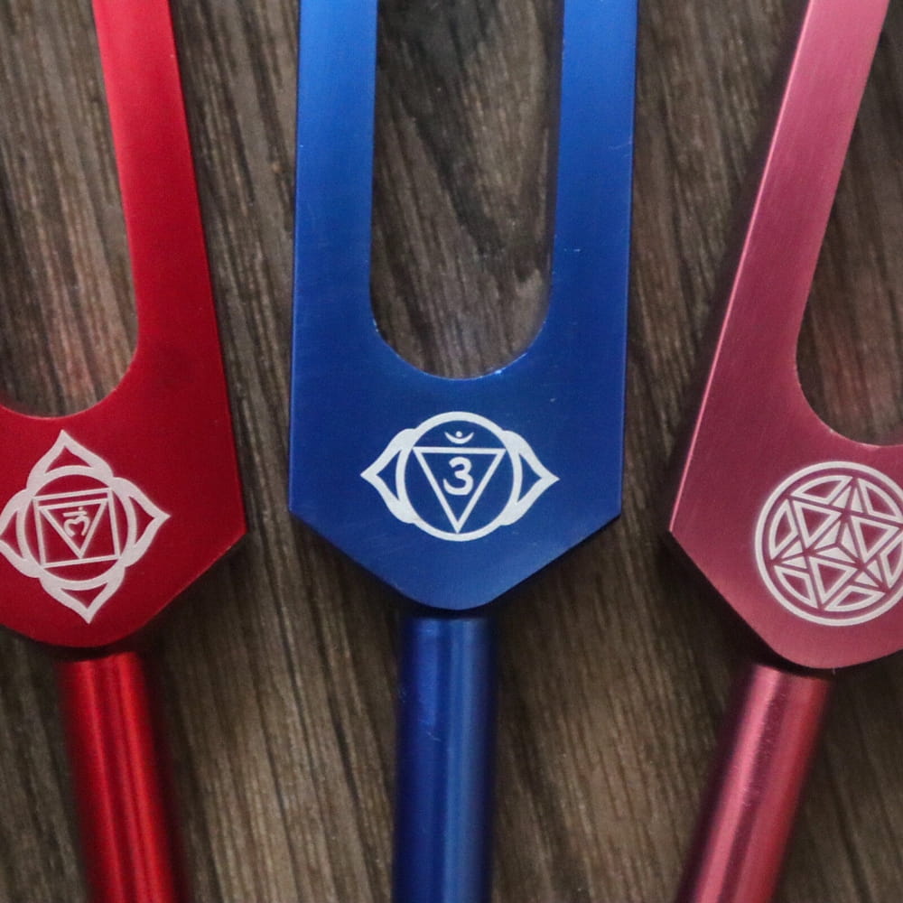Three colored tuning forks with mystical symbols for chakra and soul healing