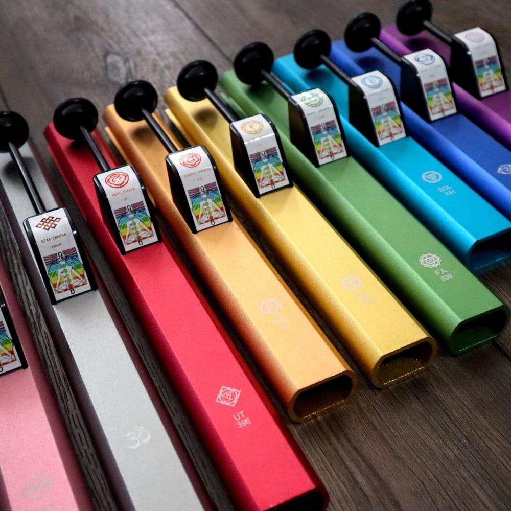 Colorful disposable vape pens lined up in a row near a Solfeggio tuning fork set