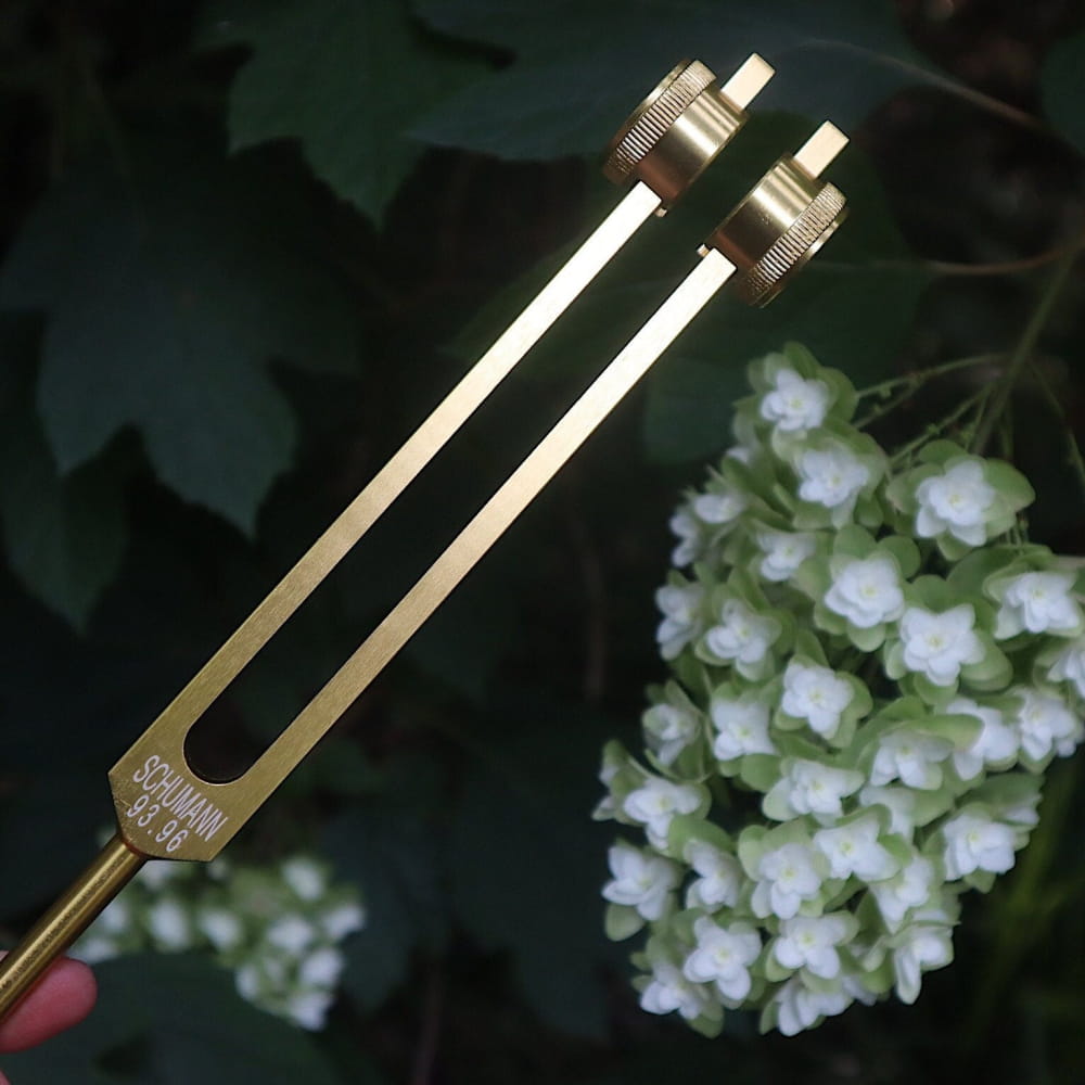 Gold-colored tuning fork with parallel prongs for 93.96 Hz Earth sound healing