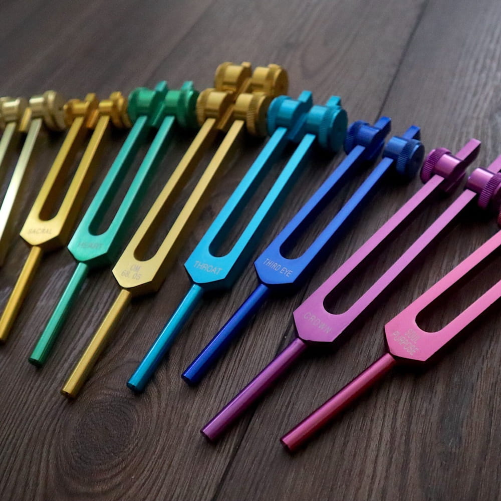 Colorful tuning forks in a row from a 9pc Chakra Tuning Fork Set for healing therapy