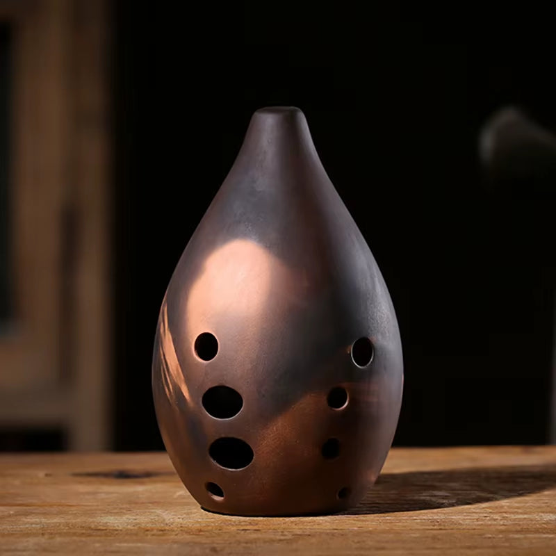 Dark ceramic vase with circular holes, showcasing the Ceramic Xun Chinese Musical Instrument