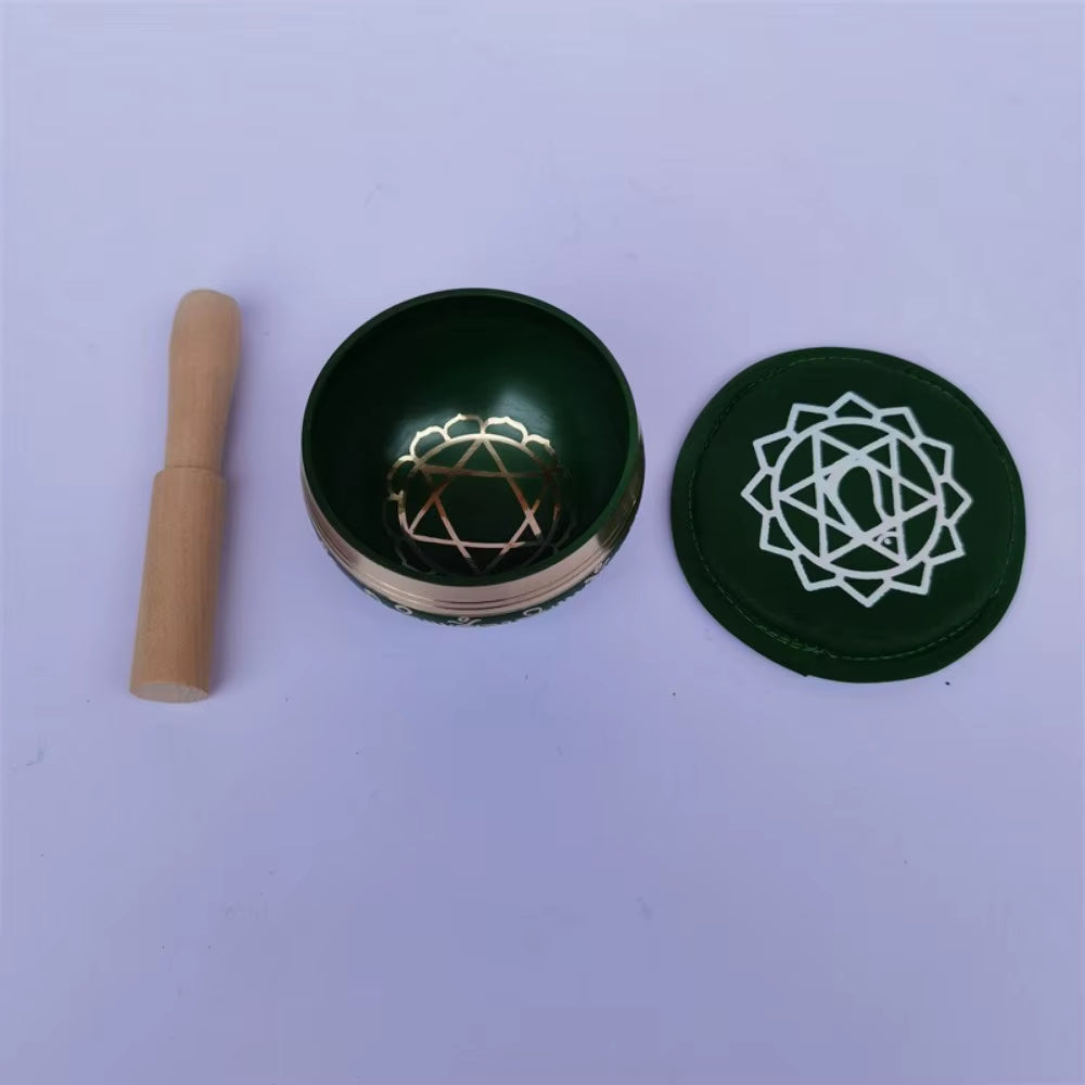 Green meditation bowls with white symbols next to a wooden stick for Tibetan singing bowl