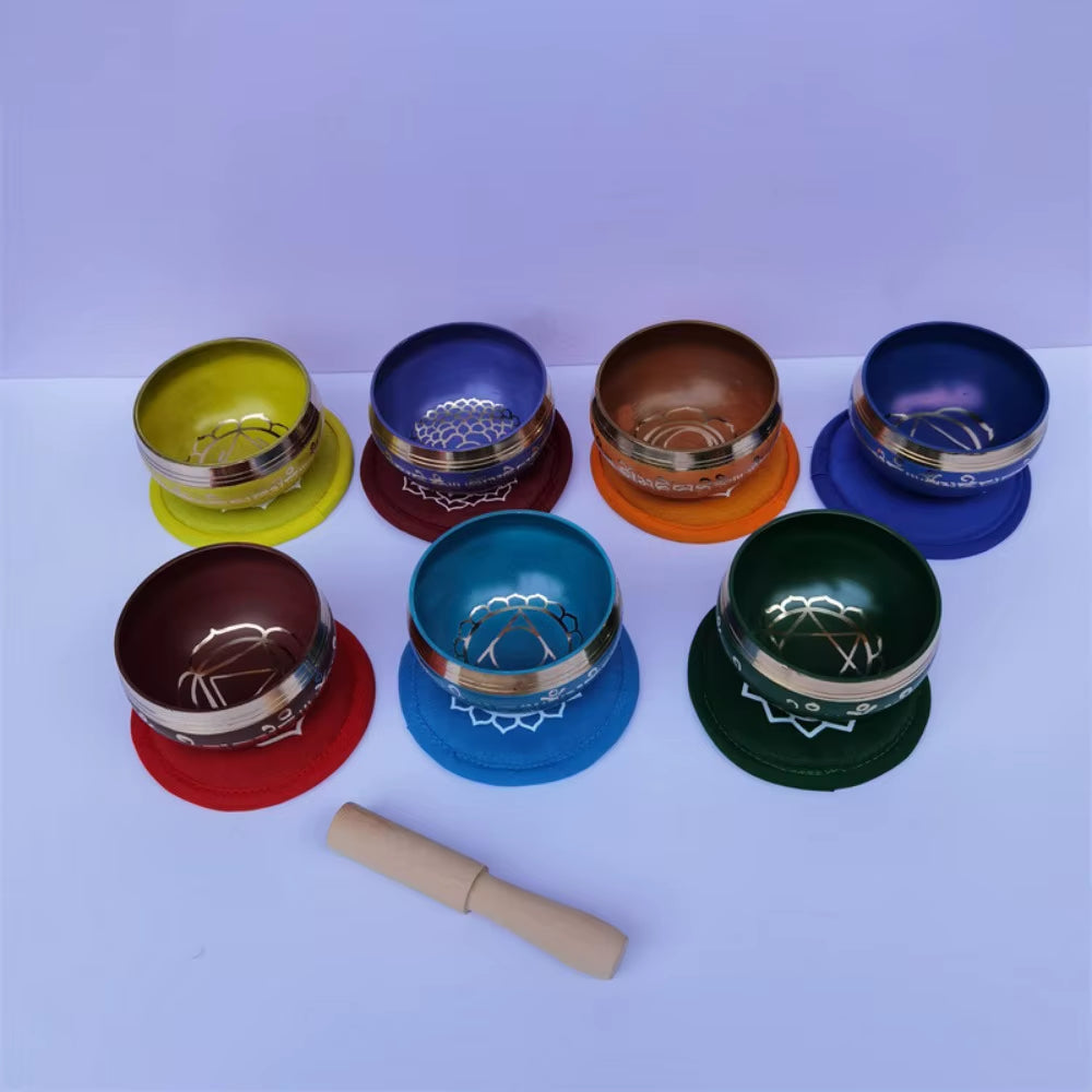 Colorful Brass Tibetan Singing Bowls in a semicircle with wooden striker for meditation