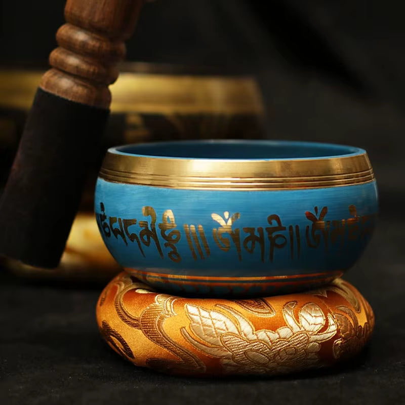 Turquoise Tibetan singing bowl with gold Sanskrit on ornate cushion for healing use