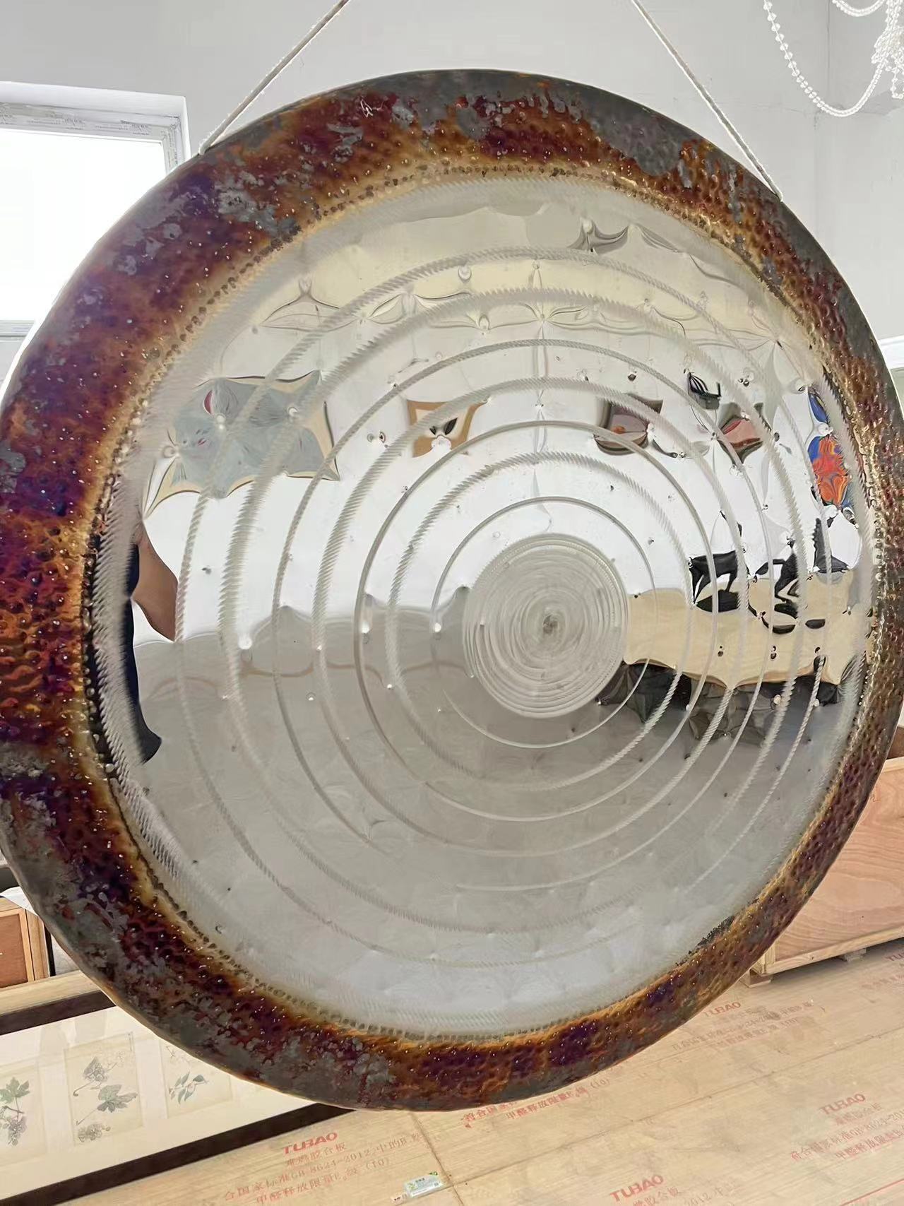 Concave circular mirror with rusty rim and spiral pattern on Luminous Gong Instrument