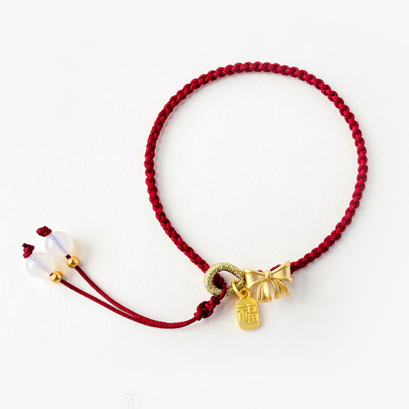 Bracelet en fil rouge avec breloque Fu et détail fleur de pêcher