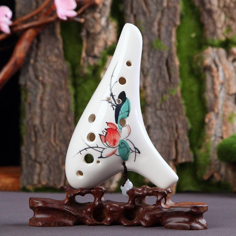 White ceramic ocarina with painted birds on a wooden stand for beginners