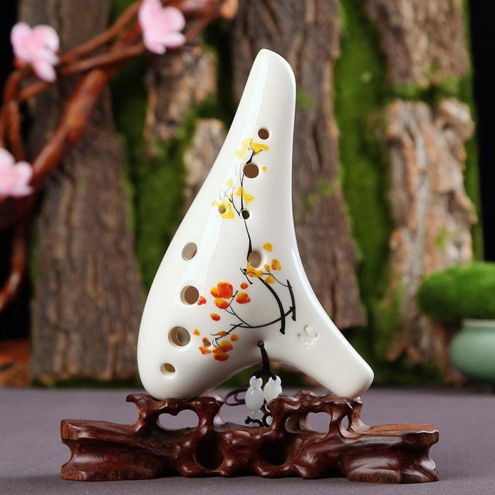 White ceramic ocarina with floral designs on wooden stand for beginners