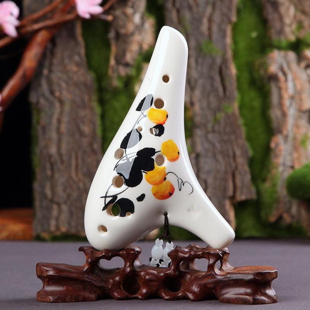 White ceramic ocarina with floral design on a wooden stand for beginners