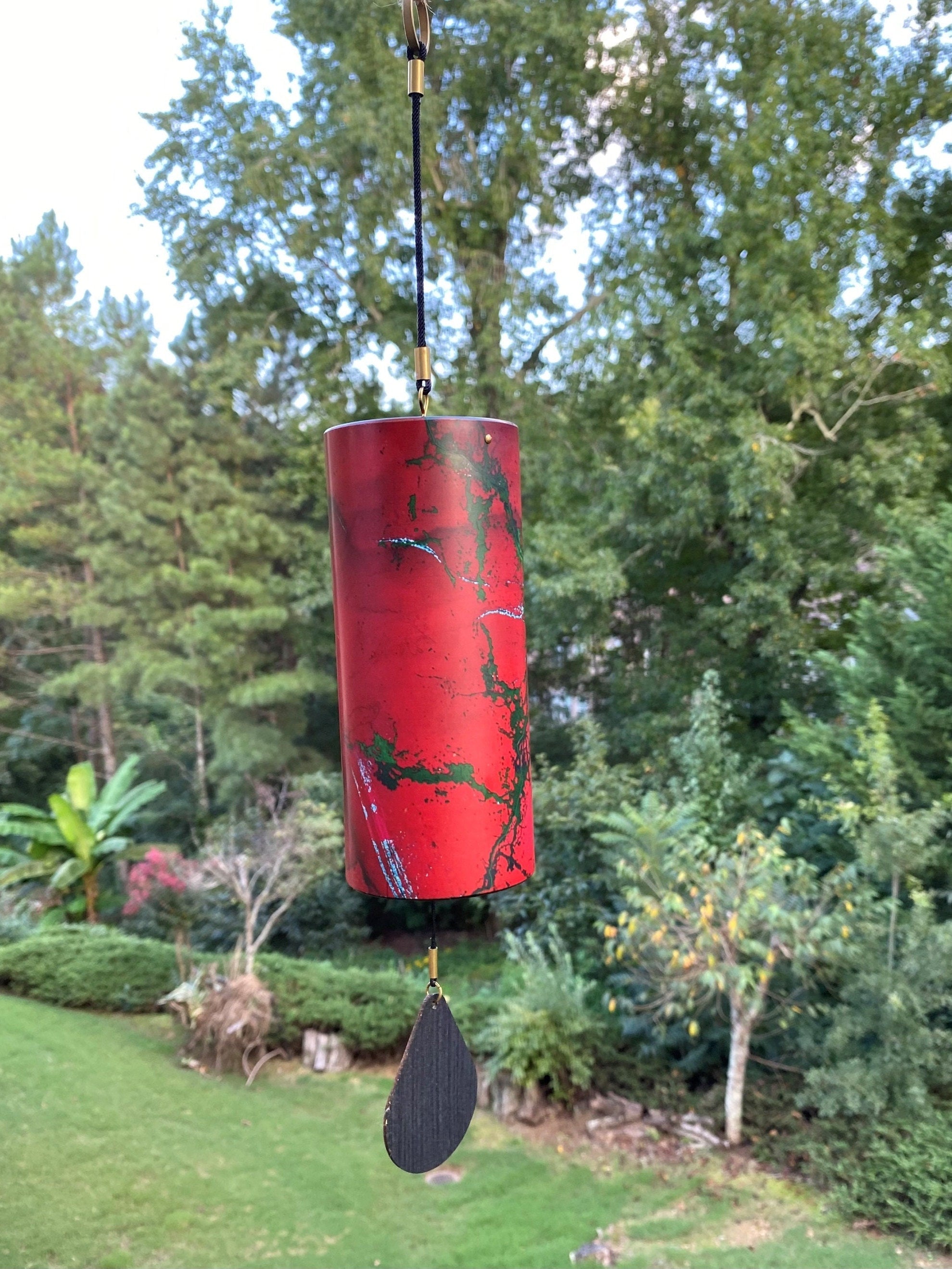 Red cylindrical wind chime with black designs and paddle for home and garden decor