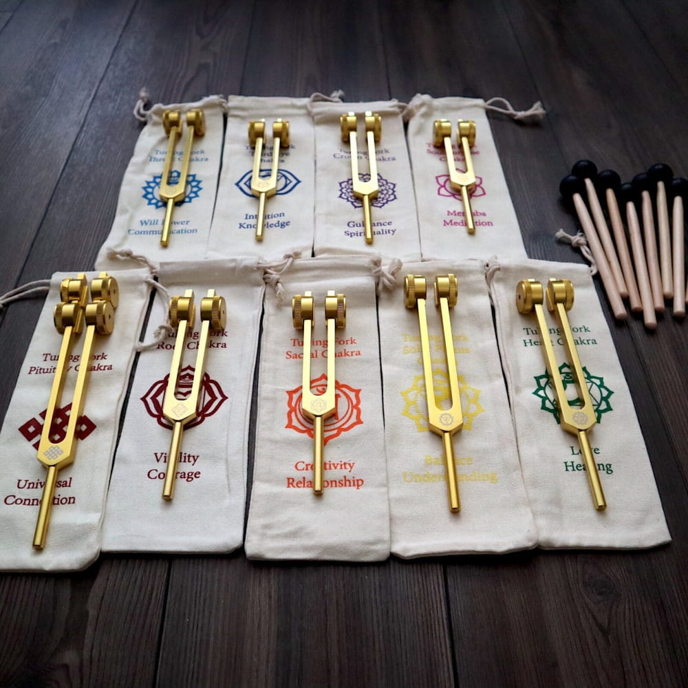 Collection of golden tuning forks in labeled pouches for chakra healing set