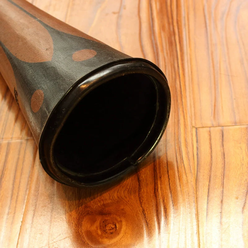 Black and gray polka-dotted party horn noisemaker next to a 55 inch Professional Didgeridoo