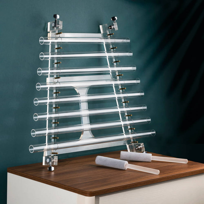 Metal and glass test tube rack on wood surface beside 8-Note Quartz Crystal Singing Harp