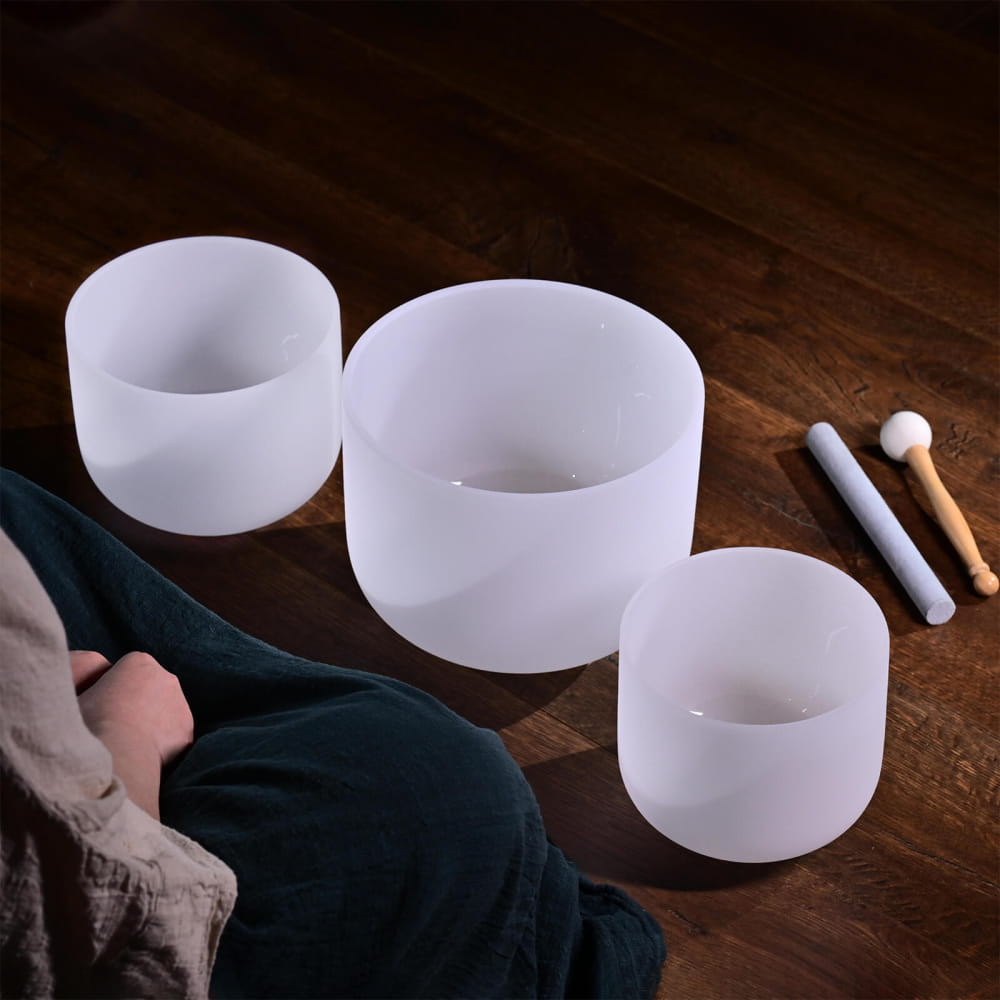 Three frosted white crystal singing bowls with mallets in a set