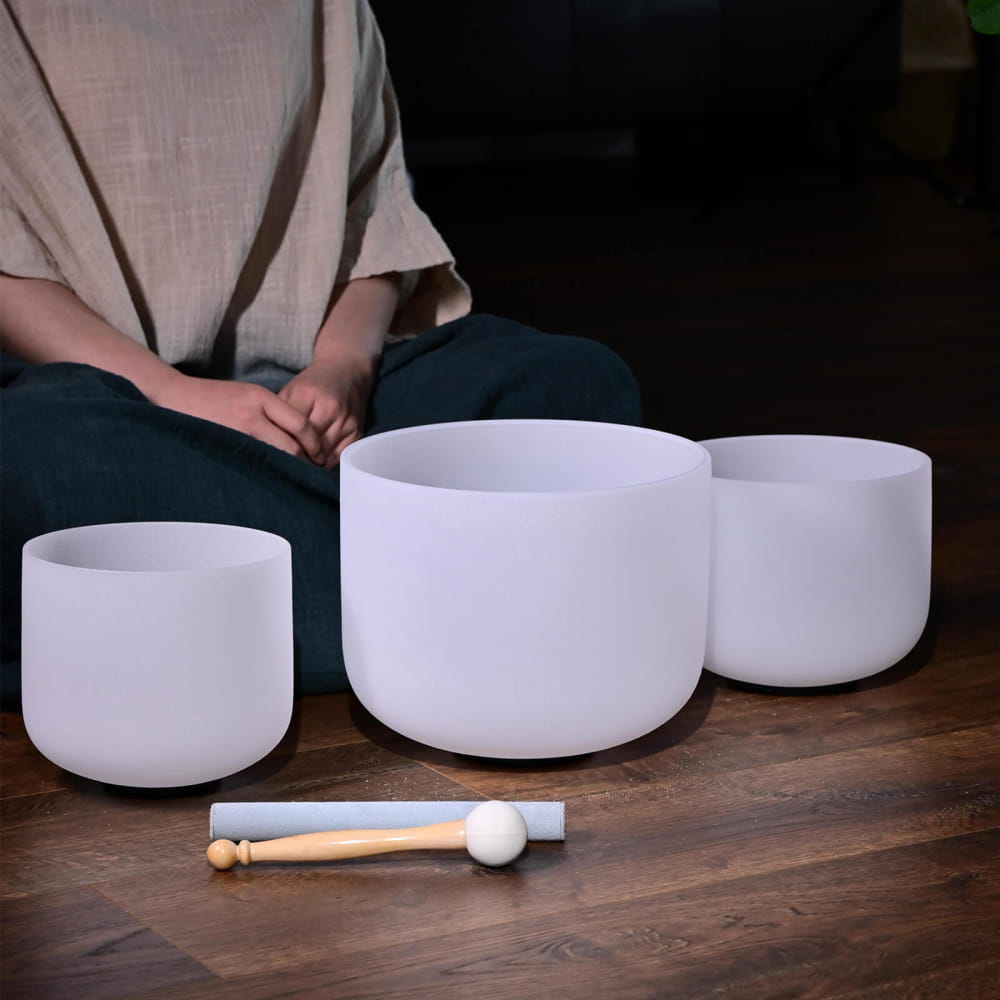 Three white crystal singing bowls with a mallet in a Frosted Quartz set