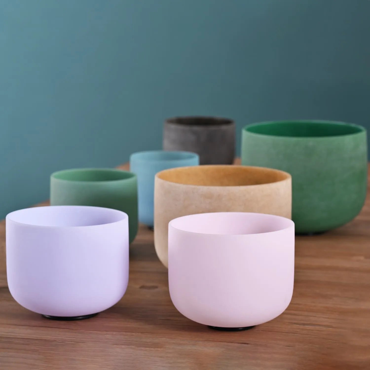 Colorful ceramic cups in pastel tones displayed with Gemstone Crystal Singing Bowl Set