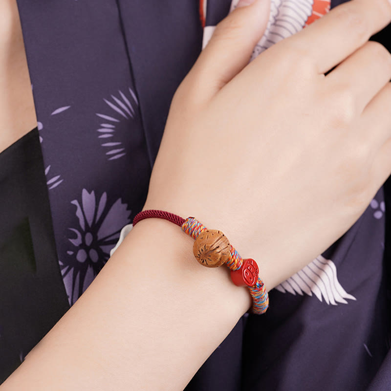 Bracelet porte-bonheur en fil rouge et cinabre avec noyau de pêche et symbole du zodiaque chinois