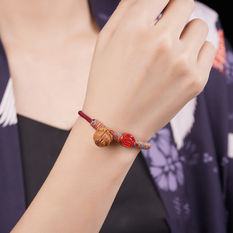 Bracelet porte-bonheur en fil rouge et cinabre avec noyau de pêche et symbole du zodiaque chinois