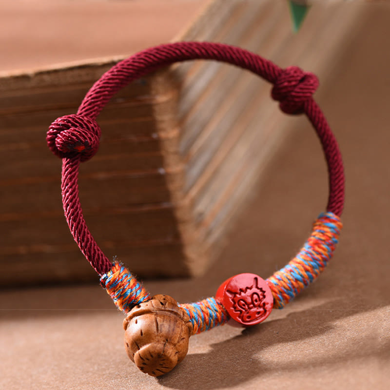 Bracelet porte-bonheur en fil rouge et cinabre avec noyau de pêche et symbole du zodiaque chinois