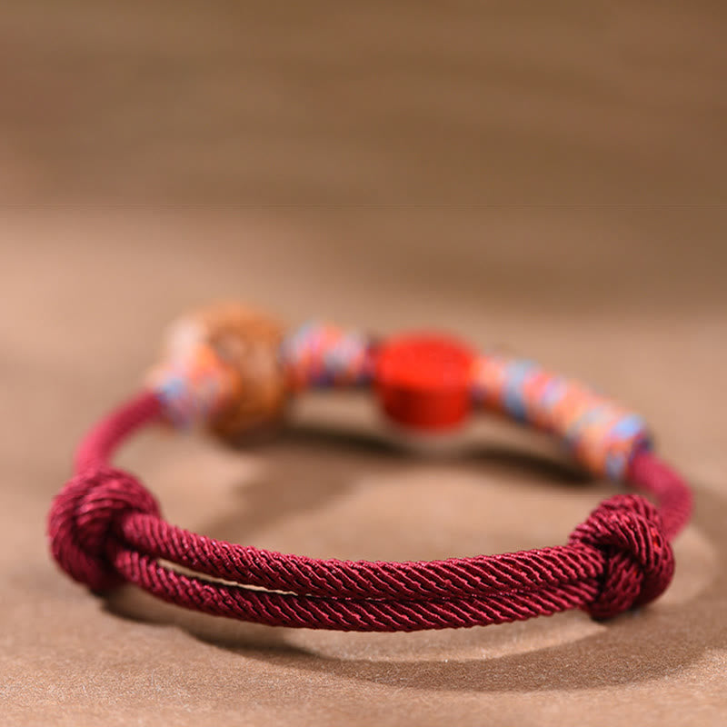 Bracelet porte-bonheur en fil rouge et cinabre avec noyau de pêche et symbole du zodiaque chinois