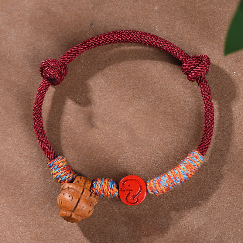 Bracelet porte-bonheur en fil rouge et cinabre avec noyau de pêche et symbole du zodiaque chinois