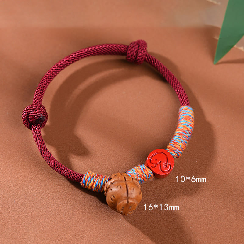 Bracelet porte-bonheur en fil rouge et cinabre avec noyau de pêche et symbole du zodiaque chinois