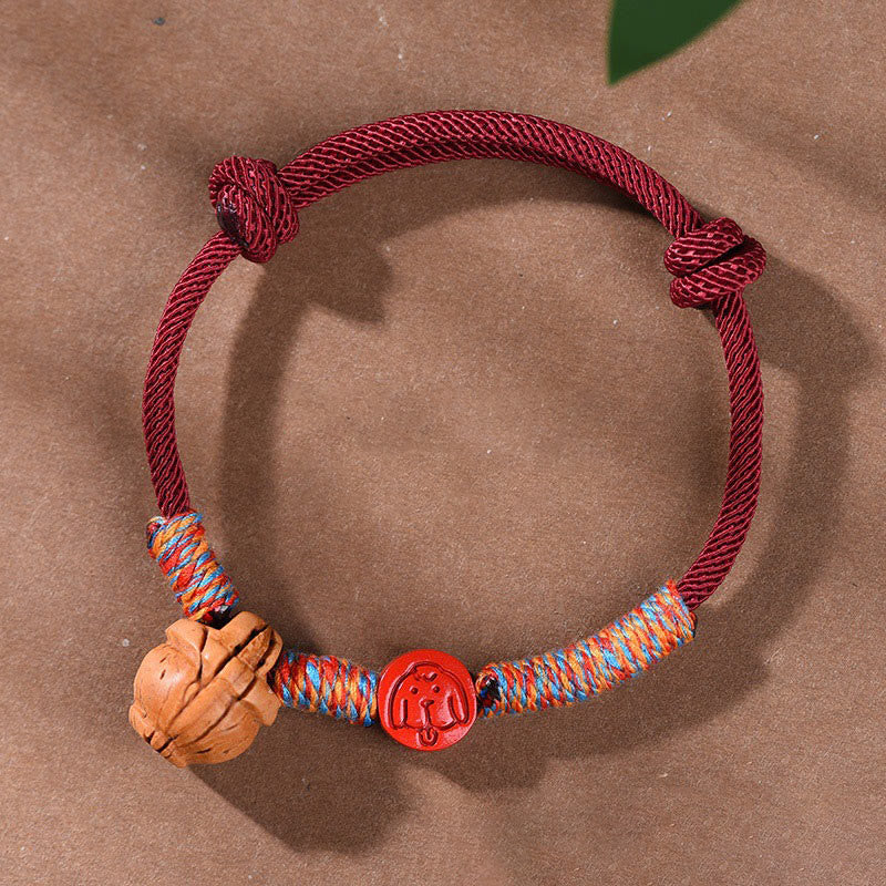 Bracelet porte-bonheur en fil rouge et cinabre avec noyau de pêche et symbole du zodiaque chinois