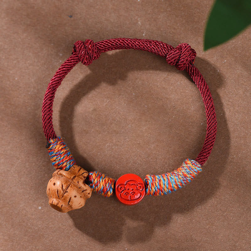 Bracelet porte-bonheur en fil rouge et cinabre avec noyau de pêche et symbole du zodiaque chinois