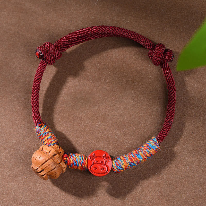 Bracelet porte-bonheur en fil rouge et cinabre avec noyau de pêche et symbole du zodiaque chinois
