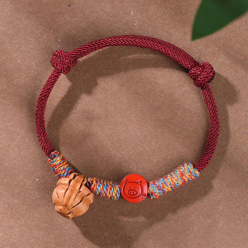 Bracelet porte-bonheur en fil rouge et cinabre avec noyau de pêche et symbole du zodiaque chinois