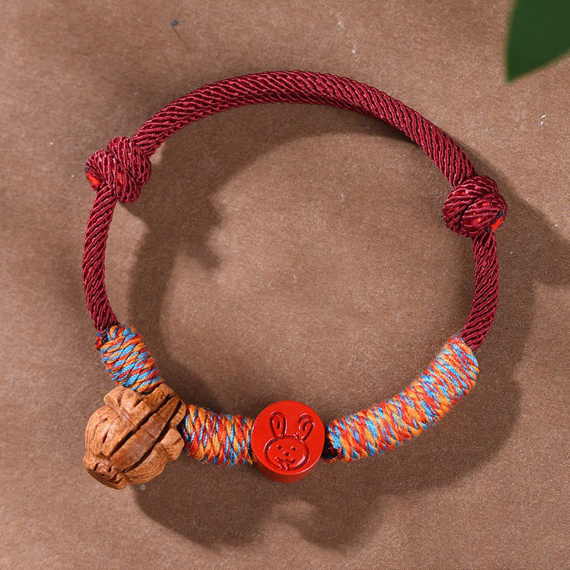 Bracelet porte-bonheur en fil rouge et cinabre avec noyau de pêche et symbole du zodiaque chinois