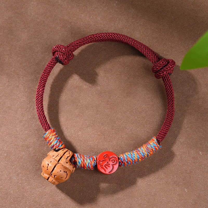 Bracelet porte-bonheur en fil rouge et cinabre avec noyau de pêche et symbole du zodiaque chinois