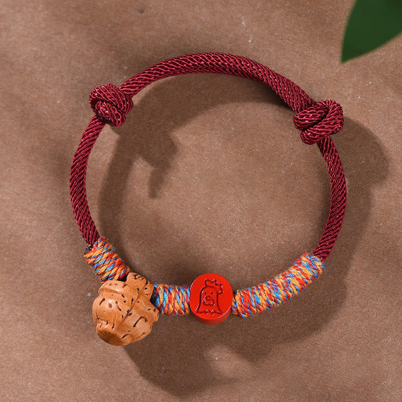 Bracelet porte-bonheur en fil rouge et cinabre avec noyau de pêche et symbole du zodiaque chinois