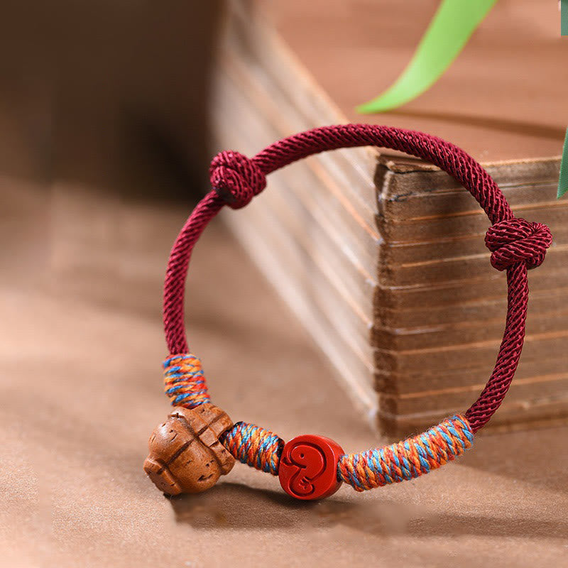Bracelet porte-bonheur en fil rouge et cinabre avec noyau de pêche et symbole du zodiaque chinois