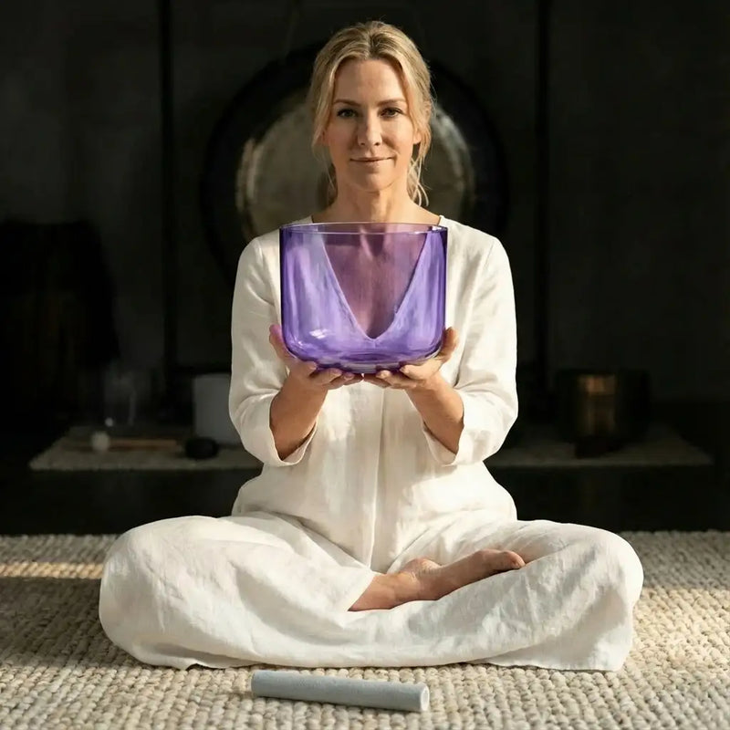A translucent purple glass singing bowl held gently in hands.