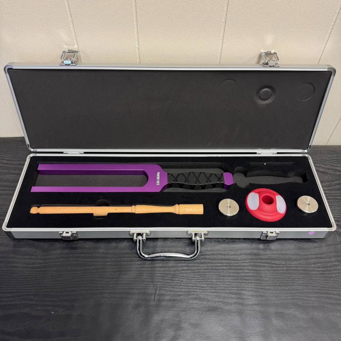 Open aluminum case with martial arts weapons and accessories next to Giant Tuning Forks