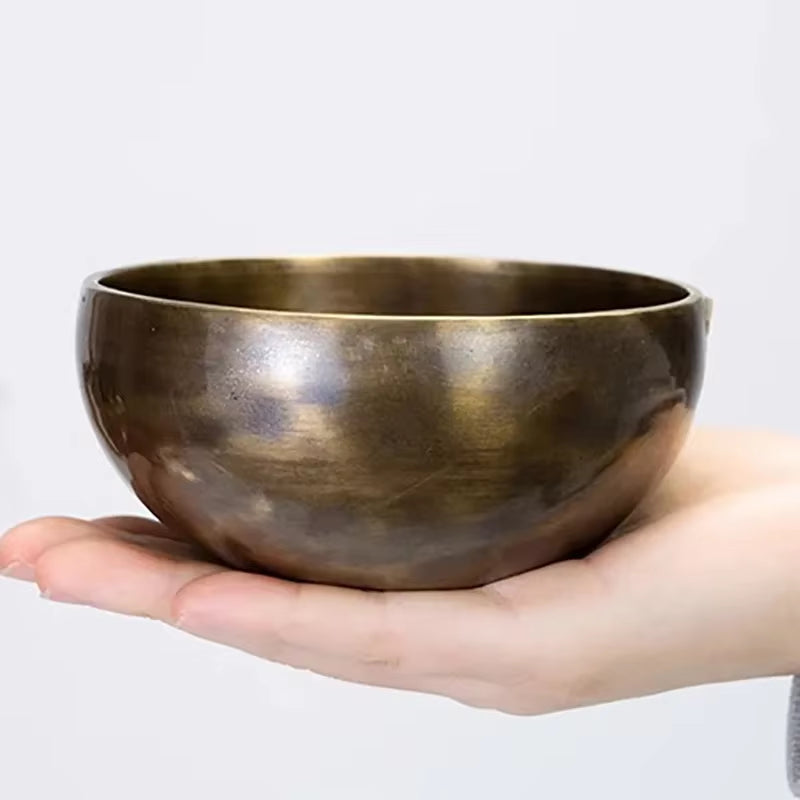 Metallic Tibetan singing bowl resting on a palm for meditation and relaxation