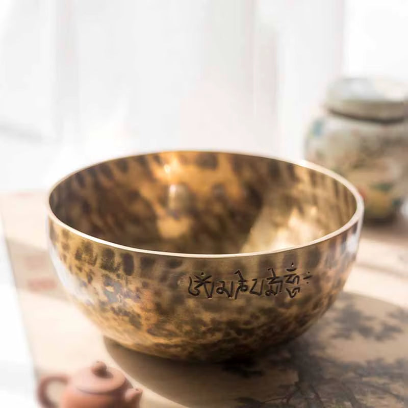 Golden Tibetan singing bowl with etched Sanskrit for healing and meditation