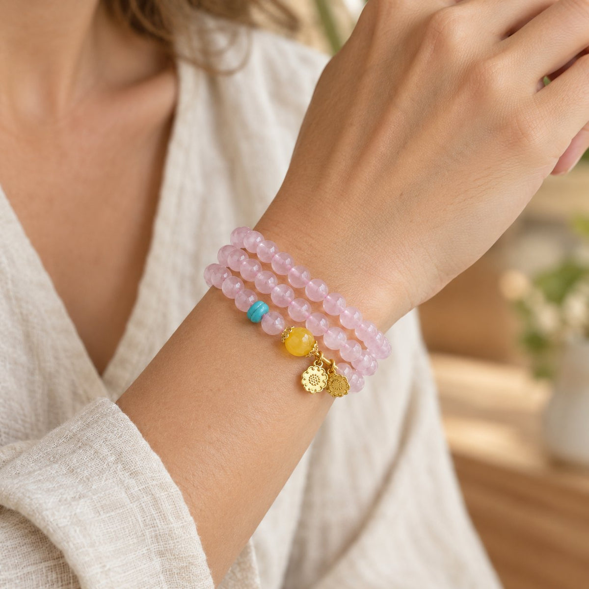 6mm Pink Crystal Lotus Bracelet with Yellow Chalcedony, worn on the wrist by a woman