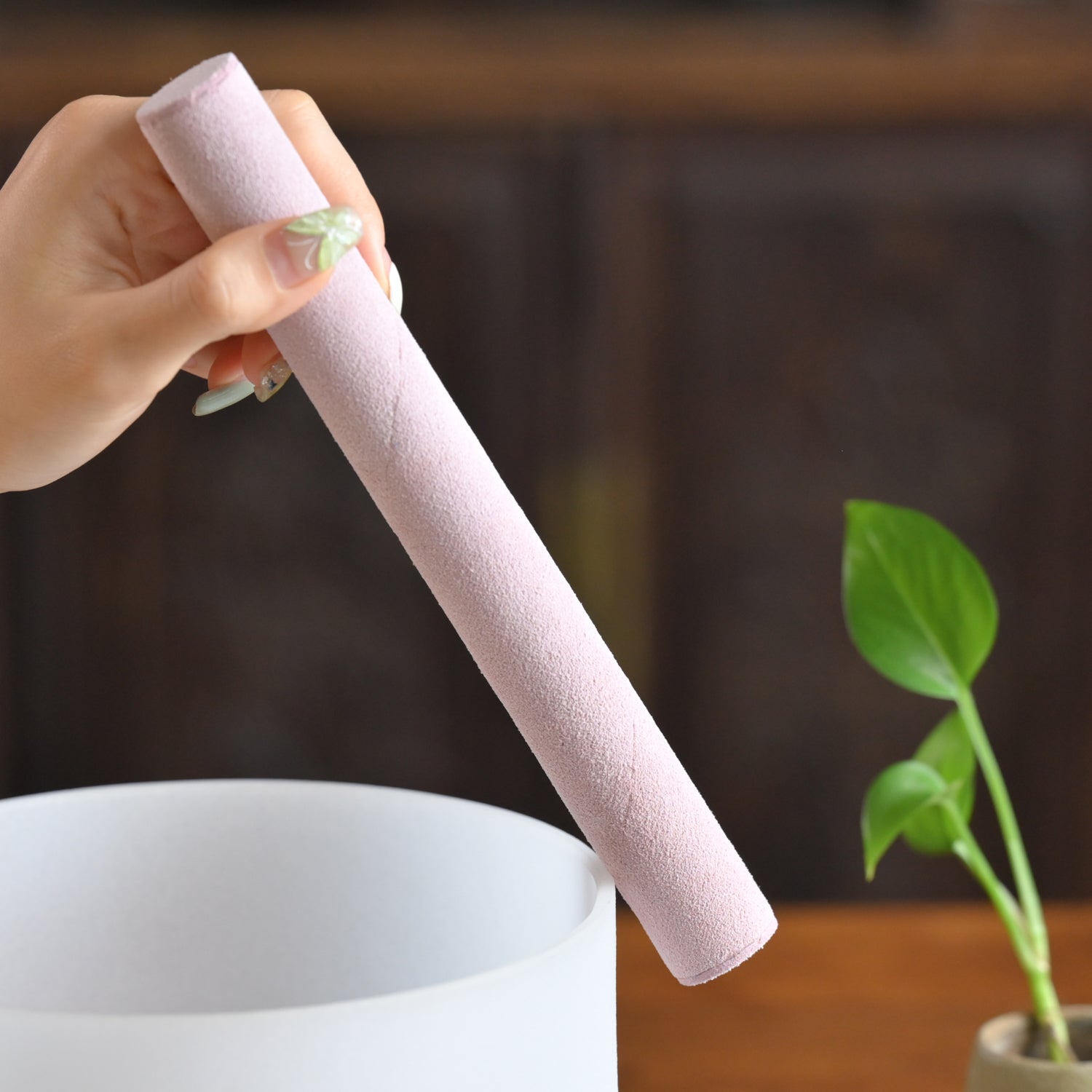 Pink cylindrical bath fizzer held over a white bowl with a Pink Suede Mallet